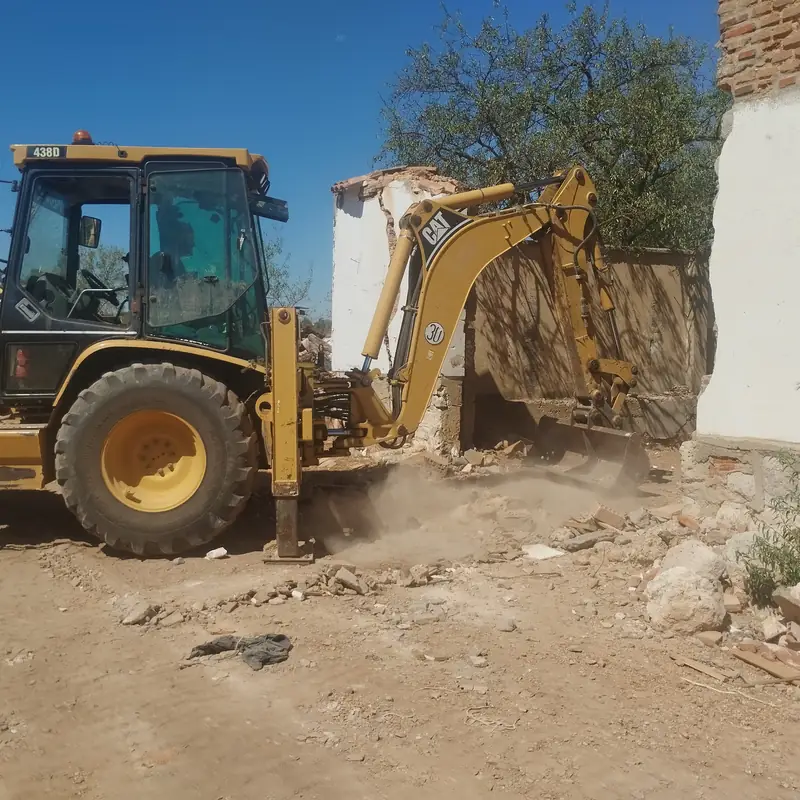 Excavadora CAT trabajando junto a la fachada